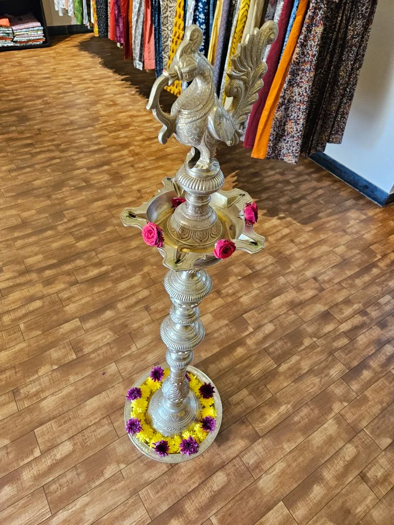 Traditional brass lamp surrounded by sarees at the MuRa@23 store