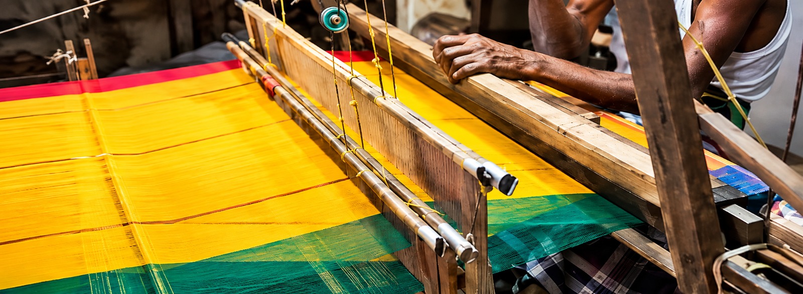 A handloom artisan weaving vibrant fabric on a traditional loom